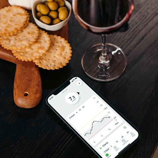 A phone lays on a table next to some holiday snacks showing the Dexcom G7 app and it's glucose insights.  